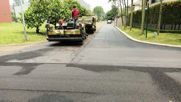 Proses penghamparan aspal hotmix menggunakan asphalt finisher di lokasi proyek pengaspalan